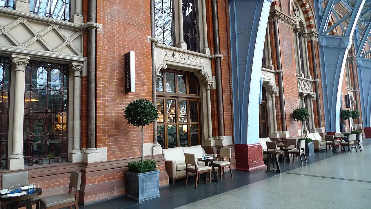 La facciata in mattoni rossi con colonne in pietra e la scritta Booking Office scolpita sopra la porta a vetri, al piano superiore della stazione di St Pancras