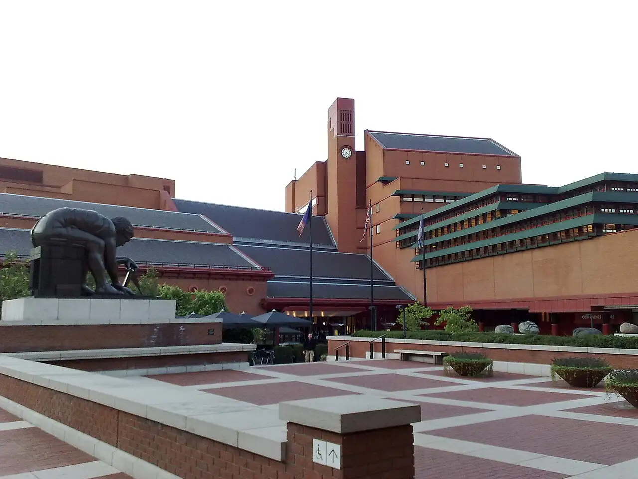 Il piazzale della British Library con la statua in bronzo di Newton di Eduardo Paolozzi, i tetti a falde e la torre dell'orologio in mattoni rossi