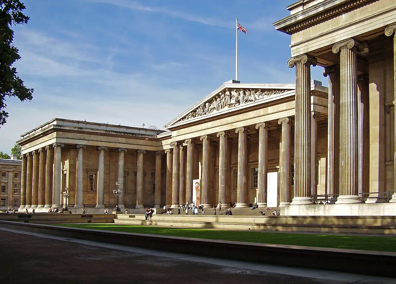 La facciata neoclassica del British Museum, con il colonnato e il frontone scolpito, vista dal cortile d'ingresso in una giornata di sole