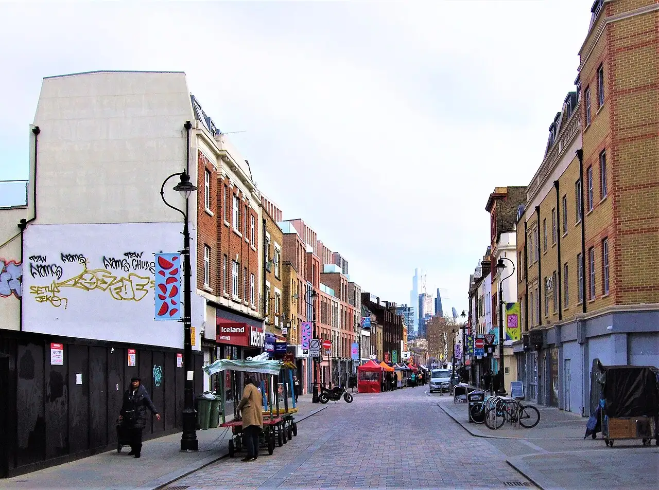 Lower Marsh in una giornata nuvolosa, con i gazebo del mercato in fondo alla strada e alcuni grattacieli sullo sfondo