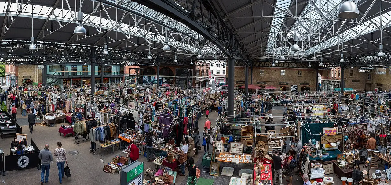 Veduta panoramica dell'interno di Old Spitalfields Market, con i banchi di abiti e antiquariato sotto il tetto in ferro e vetro