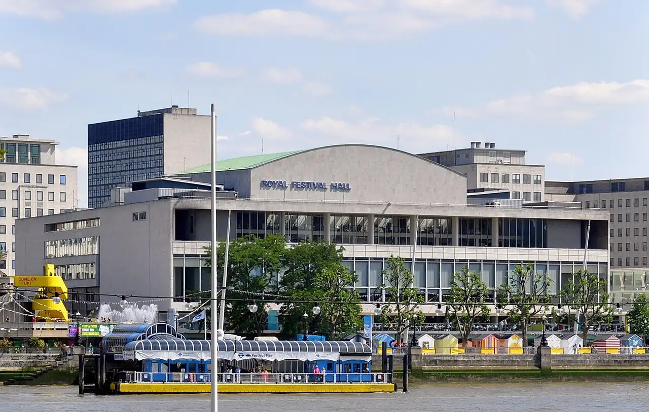 La Royal Festival Hall vista dalla riva nord del Tamigi, con la scritta sulla facciata e il pontile sul fiume in primo piano