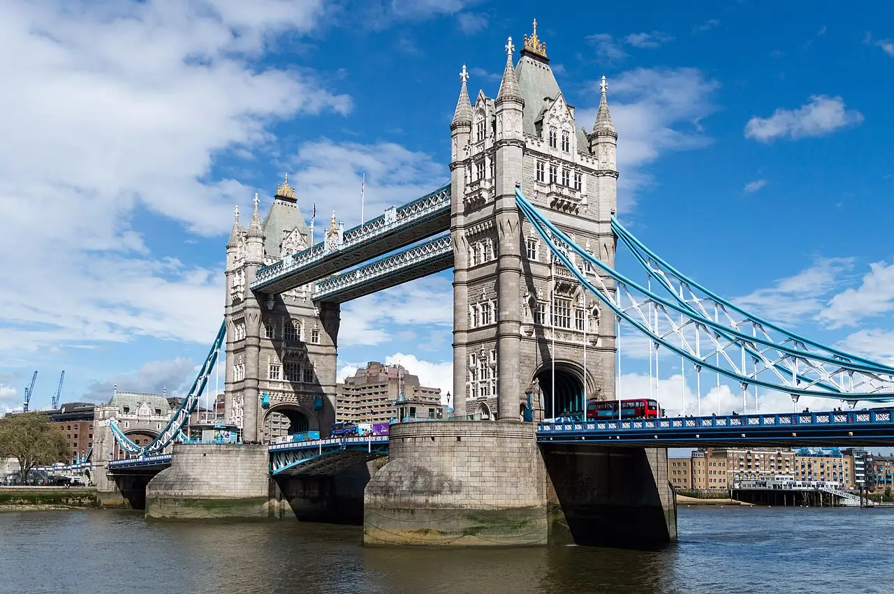 Il Tower Bridge visto dalla riva sud del Tamigi in una giornata di sole, con le due torri, le passerelle alte e un autobus rosso